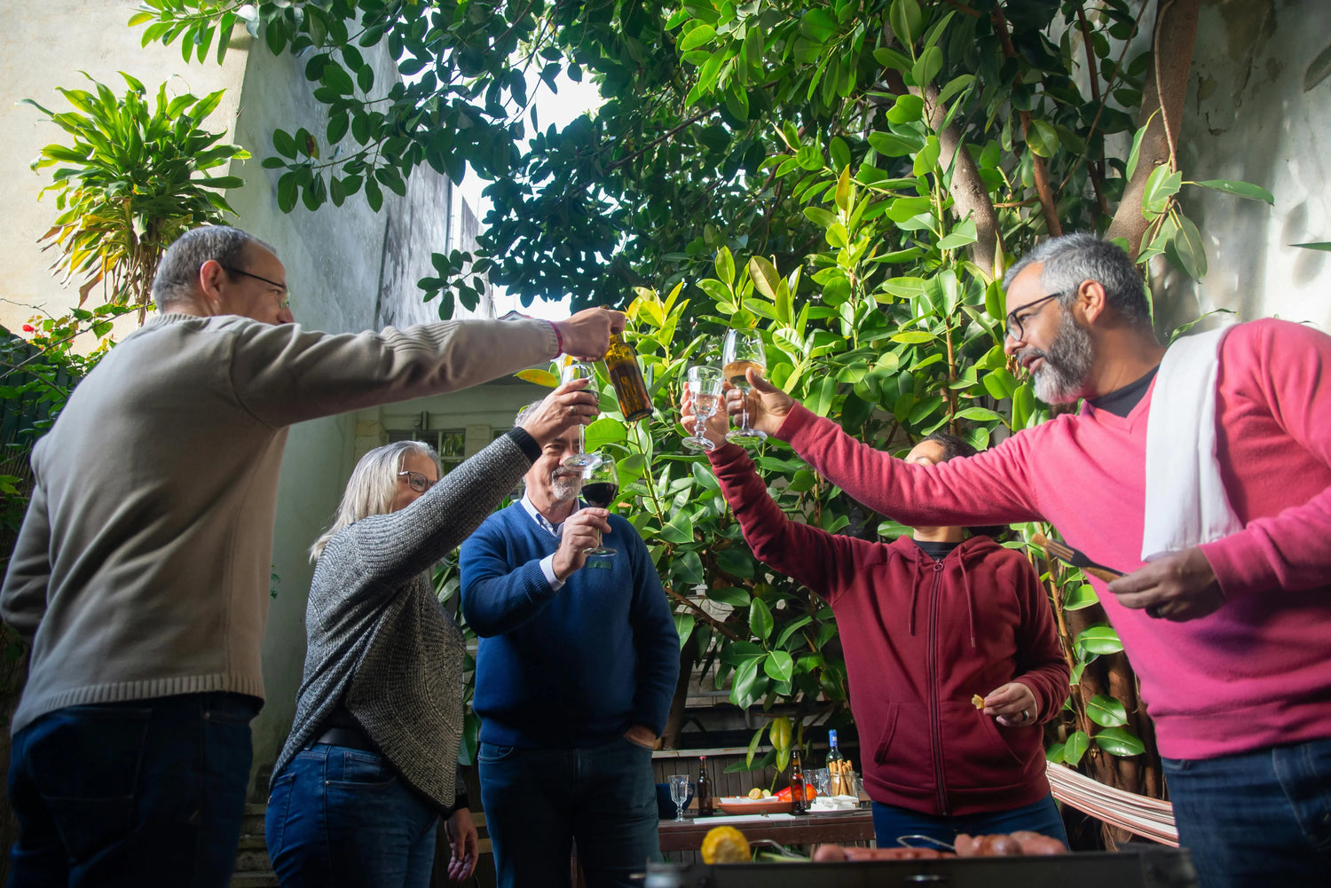 Older adults celebrating together with drinks in a lush garden setting